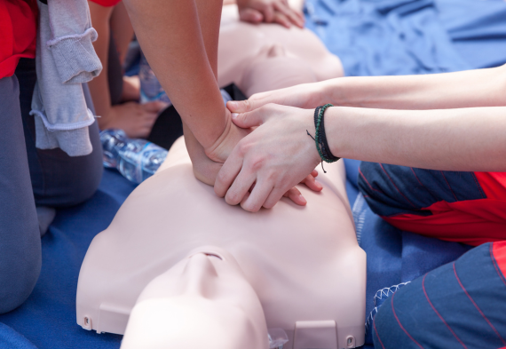 A person teaching CPR to another using a mannequin. 
