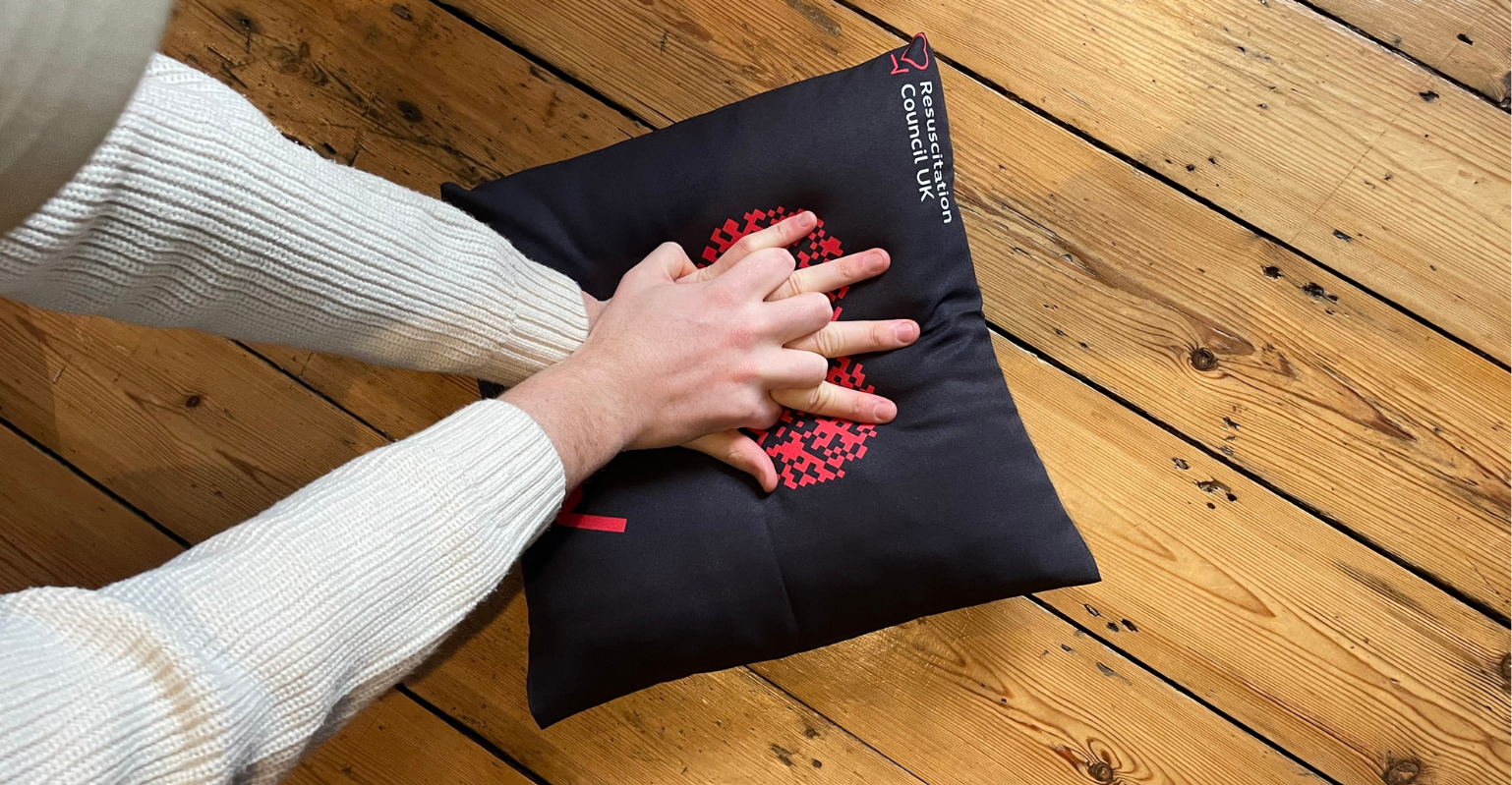 Person practicing CPR on pillow. 
