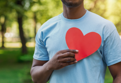 person holding a giant red paper heart over their chest