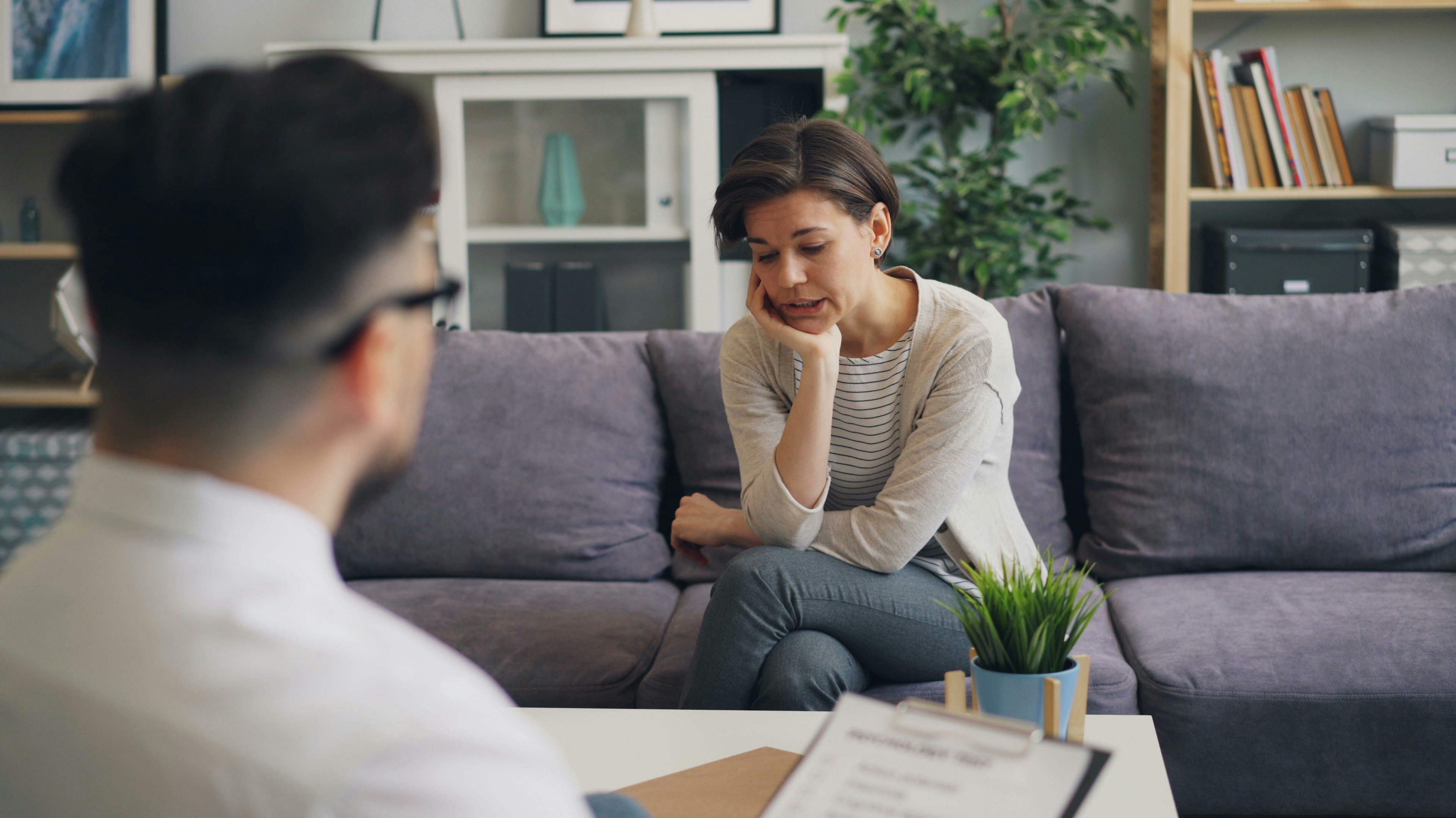 person sitting on a couch looking upset and talking to a professional