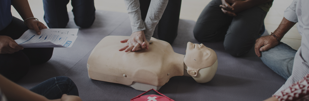 Group of people watching CPR demonstration on manikin