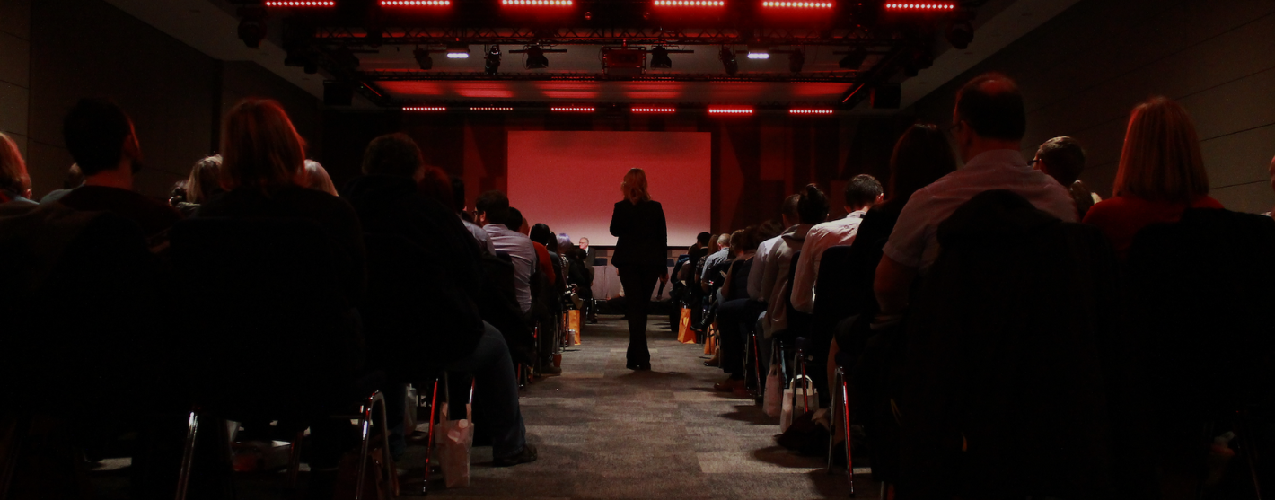 Woman standing in front of an auditorium of people.