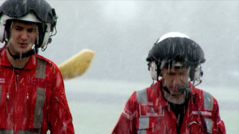 Two men walking from a helicopter in the rain