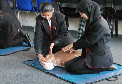 Two school children doing CPR on manikin