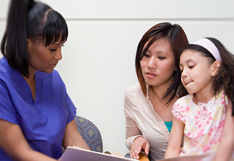 A healthcare professional explaining a form to a mother and young child