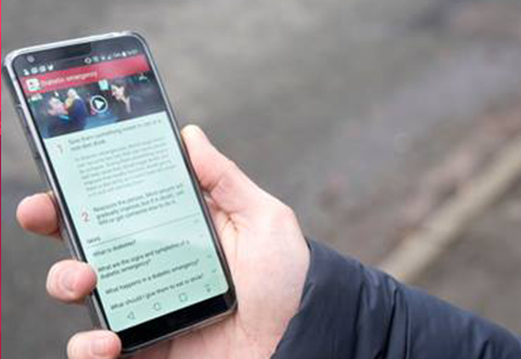 A hand holding a mobile phone which has the first aid app loaded on it. 
