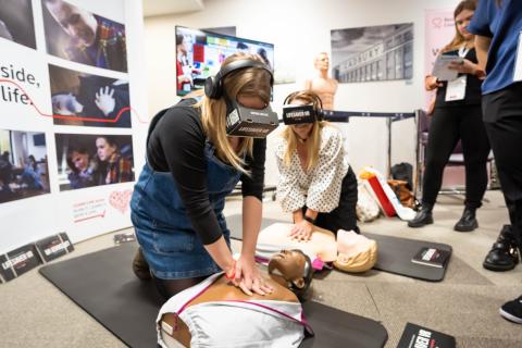 Image of a woman doing CPR on a manikin with VR headset