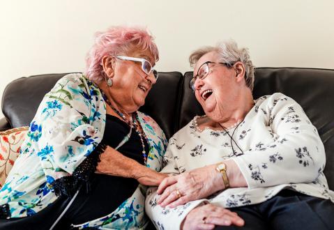 Two women laughing together on a sofa