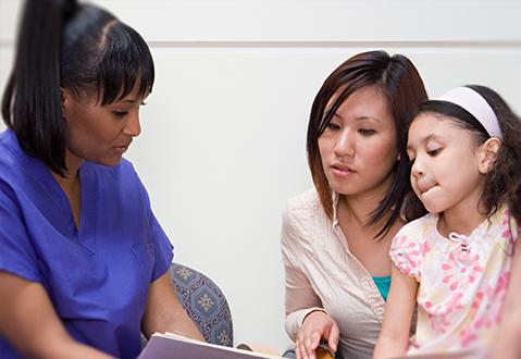 A female health care professional explaining a form to a mother and young child