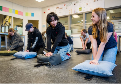 School children practicing CPR on pillows 