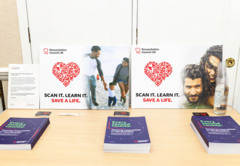 Copies of the every second counts report on table. Campaign placards displayed in background. 