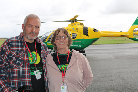 Nina, a cardiac arrest survivor, standing with her husband in front of the Ambulance service helicopter.