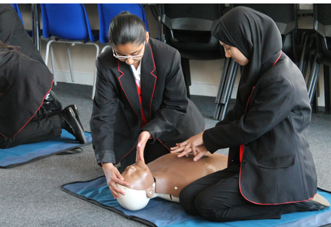 two school students practicing CPR on a training manikin