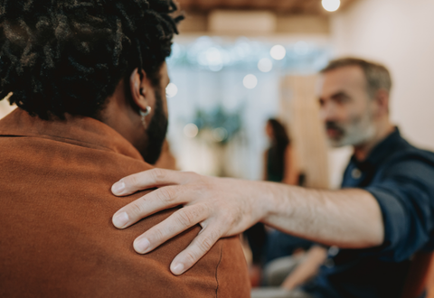 A man resting his hand on the shoulder of another man as a way to show support