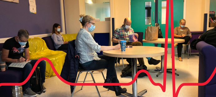 People wearing masks and socially distancing within a hospital environment.