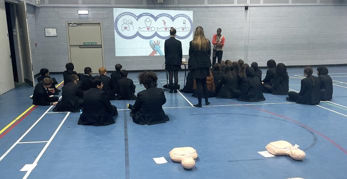 school children sitting in school gymnasium learning about CPR