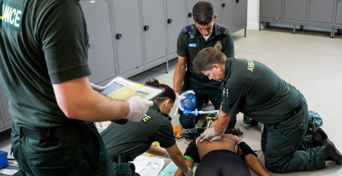 pre-hospital healthcare professionals attending to a woman having a cardiac arrest inside a locker room
